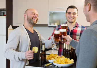 Fototapeta na wymiar Three men with beer at kitchen
