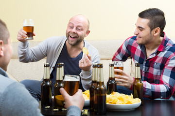 Three happy friends drinking beer