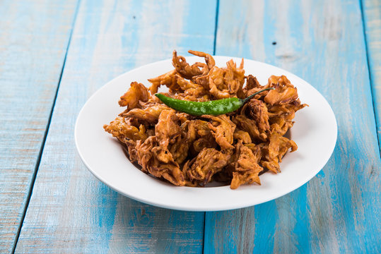 Onion Bhajis or onion pakora or kanda bhaji served with fried green chilli