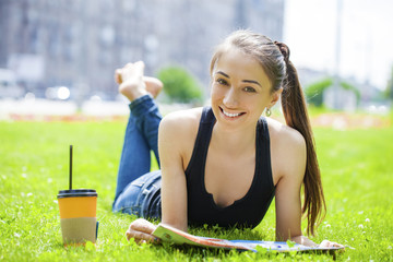 Young woman reading magazine lying on grass