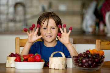 Cute little boy, eating fruits - strawberries, cherries, raspber