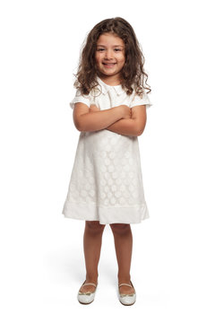 Portrait of a happy little girl on white background looking at the camera smiling arms crossed