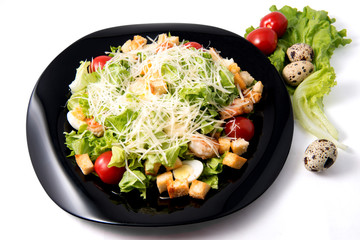 Caesar salad with prawns, cherry tomato and cheese on black plate