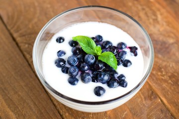 Homemade yogurt with fresh blueberries on a wooden table