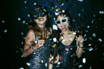 Two young women in masks dancing at the party