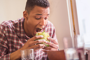 Picture of hungry man eating vegan burger in vegan restaurant or cafe. Handsome man following vegan...