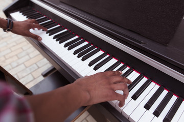 Fototapeta na wymiar Closeup picture of of keyboard of piano. Black man playing piano outdoors in city centre. Professional musician playing piano.