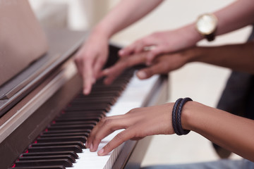 Professional musician playing outdoors. Closeup of keyboard of piano. Man playing piano while lady explaining him something.