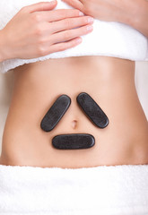 Hot stones on a woman's tummy in a triangle shape around the belly button