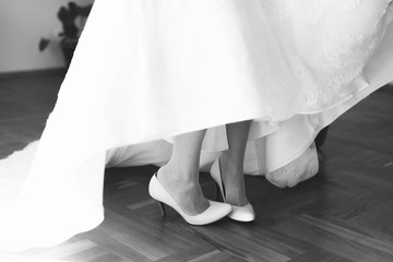 Plakat Closeup of bride's legs in white wedding shoes