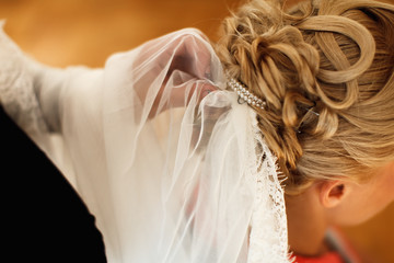 Fototapeta na wymiar Bridal veil is put on a lady's hair