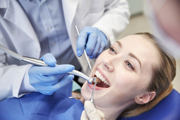 Fototapeta premium close up of dentist treating female patient teeth