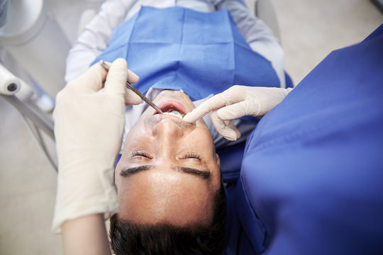 close up of dentist checking male patient teeth