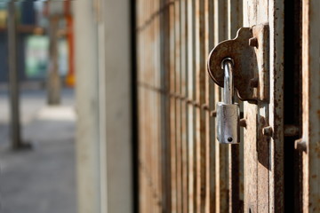 Old rust metal door locked with silver padlock closeup