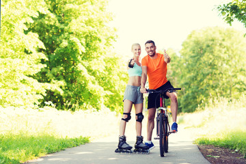 Obraz premium couple on rollerblades and bike showing thumbs up