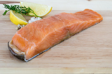 Salmon fillets fresh with lemon coriander salt and pepper on a wooden floor.