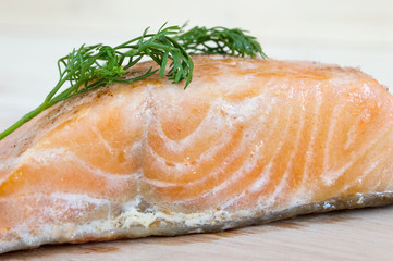 Salmon steak with lemon and coriander on a wooden floor.