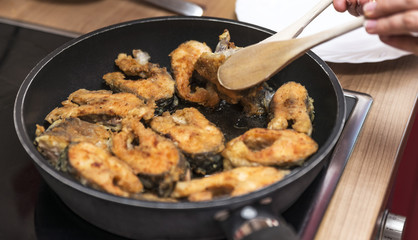  process of roasting fish in oil in a frying pan at home in the kitchen