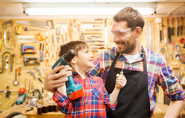 father and son with drill working at workshop
