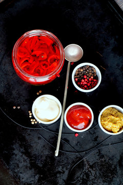 Spices - hot chili pepper, mustard, pepper - and sauces -white, mayoneese, spicy oil - on the black natural background with spoon