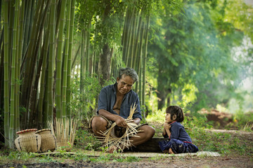 The experienced grandfather explains grandson the weaving know how.