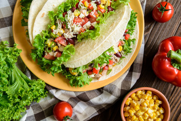 Mexican tacos with meat, beans, lettuce, corn, onion, tomato and 