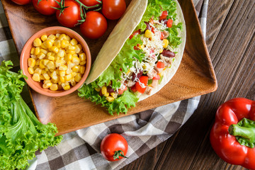 Mexican tacos with meat, beans, lettuce, corn, onion, tomato and 