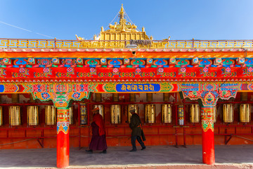 Buddhist monk walking touch a prayer wheels around the sanctuary at Larung gar (Buddhist Academy)...