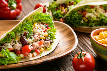 Mexican tacos with meat, beans, lettuce, corn, onion, tomato and 