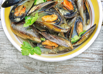 Mussel soup with fresh parsley on wooden table