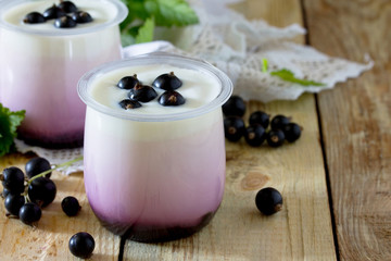 Homemade yoghurt with a black currant on the table in a rustic s