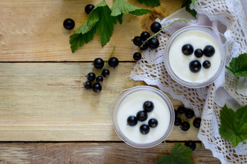 Obraz na płótnie Canvas Homemade yoghurt with a black currant on the table in a rustic s