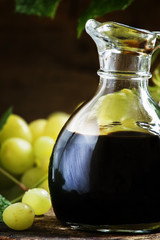 Balsamic vinegar in a glass jug, vintage wooden background, rust