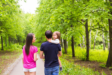 Fototapeta premium Happy young family walking down the road outside in green nature