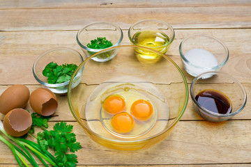 Raw eggs and ingredients on  wooden background. Vegetarian food, health or cooking concept.