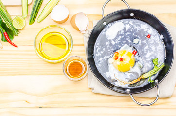 Chicken eggs in a frying pan over a vintage old wooden table. Ingredients for cooking. Rustic style. View from above.