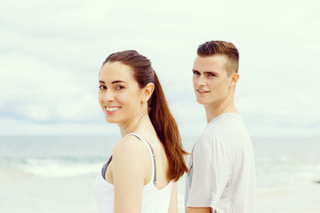 Young couple looking at camera while standing next to each other on beach