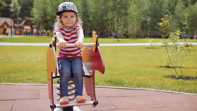little child girl play in a park sit on swing