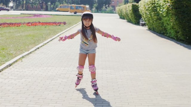 Beautiful girl on a sunny day, riding on roller skates. / Beautiful girl on a sunny day, riding on roller skates. Girl in shorts and a striped T-shirt with a picture roller skates skating smiling.