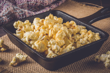 Salt popcorn cooked in black pan on the table.