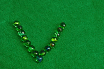 The letter V made out of marbles on a green background