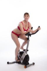 WOMAN RIDING AN EXERCISE BIKE - A mid age woman wearing red underwear riding an exercise bicycle