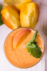 Smoothie in a glass and slices of fresh peaches