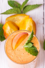 Smoothie in a glass and slices of fresh peaches