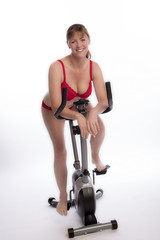 Fototapeta na wymiar WOMAN RIDING AN EXERCISE BIKE - A mid age woman wearing red underwear riding an exercise bicycle