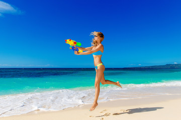 Naklejka na ściany i meble Young beautiful girl in blue bikini having fun on a tropical bea