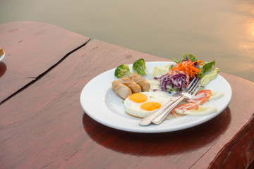 Breakfast plate on wooden table at terrace in the morning.