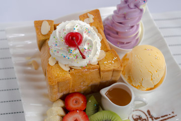 French toast with ice cream and fruit on a white plate.