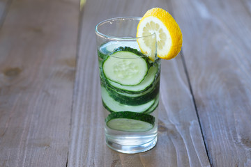 Glass of freshness water with cucumber on wooden background