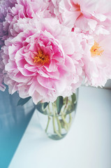 Beautiful bouquet of pink peonies, peony roses flowers in vase on white window sill, pastel color background. Spring or summer lovely nosegay. Fresh floral, home decor. Trend . Text, copy space